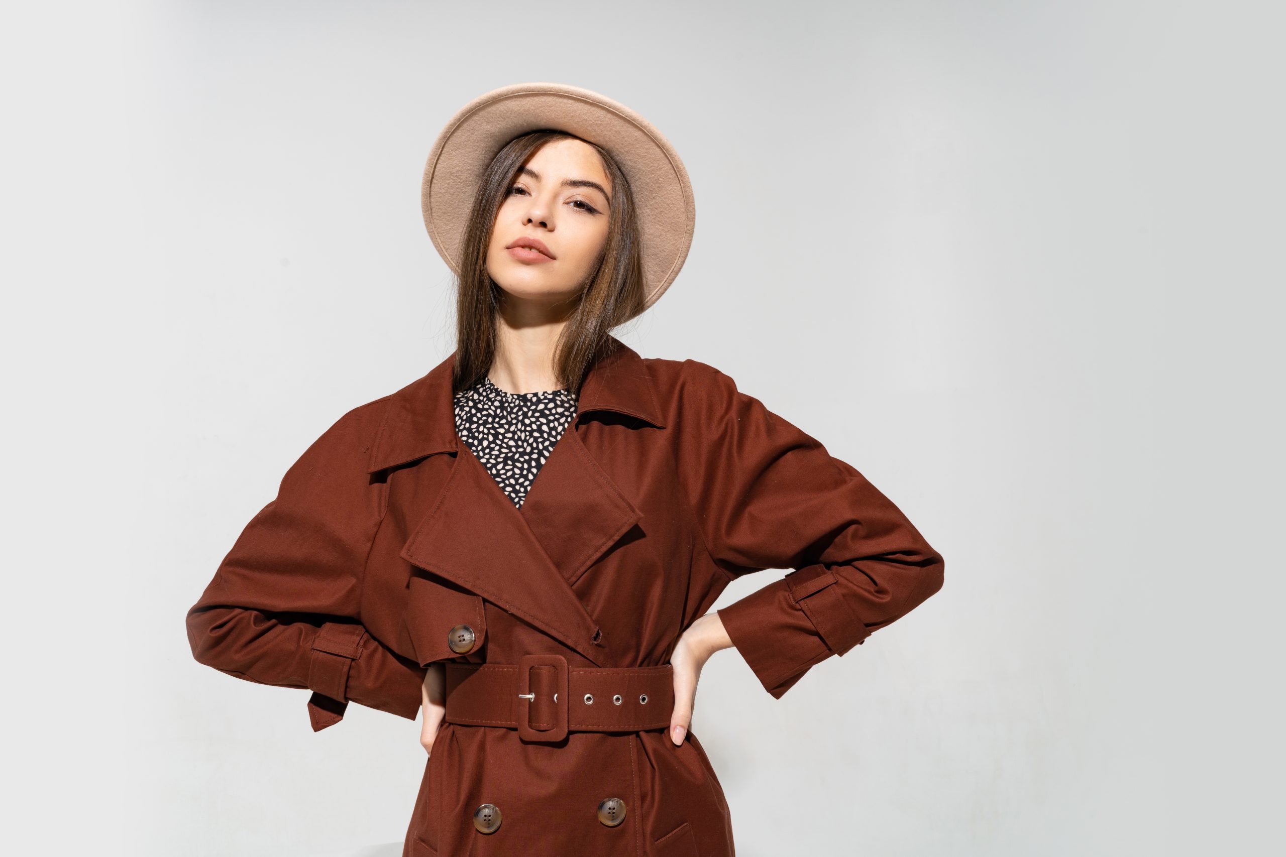 mulher elegante com casaco marrom e chapeu bege posando scaled